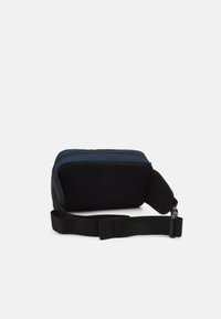 Kompakt rektangulær bag i marineblå og sort, med slidstærkt stof, lynlåslukning og en aftagelig sort rem for alsidighed.