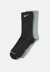 Sosete ribbate negre și gri deschis cu un logo Nike pe perechea neagră; ambele au vârfuri întărite și o textură netedă.