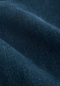 Tume sinine denimpaber, millel on twill-kudumine, millel on peened jooned ja sile, veidi läikiv pind.