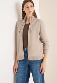 Beige Kapuzenpullover mit hohem Kragen und zwei-Wege-Reißverschluss. Verfügt über gerippte Bündchen und Saum, ein strukturiertes Strickmuster und lange Ärmel.