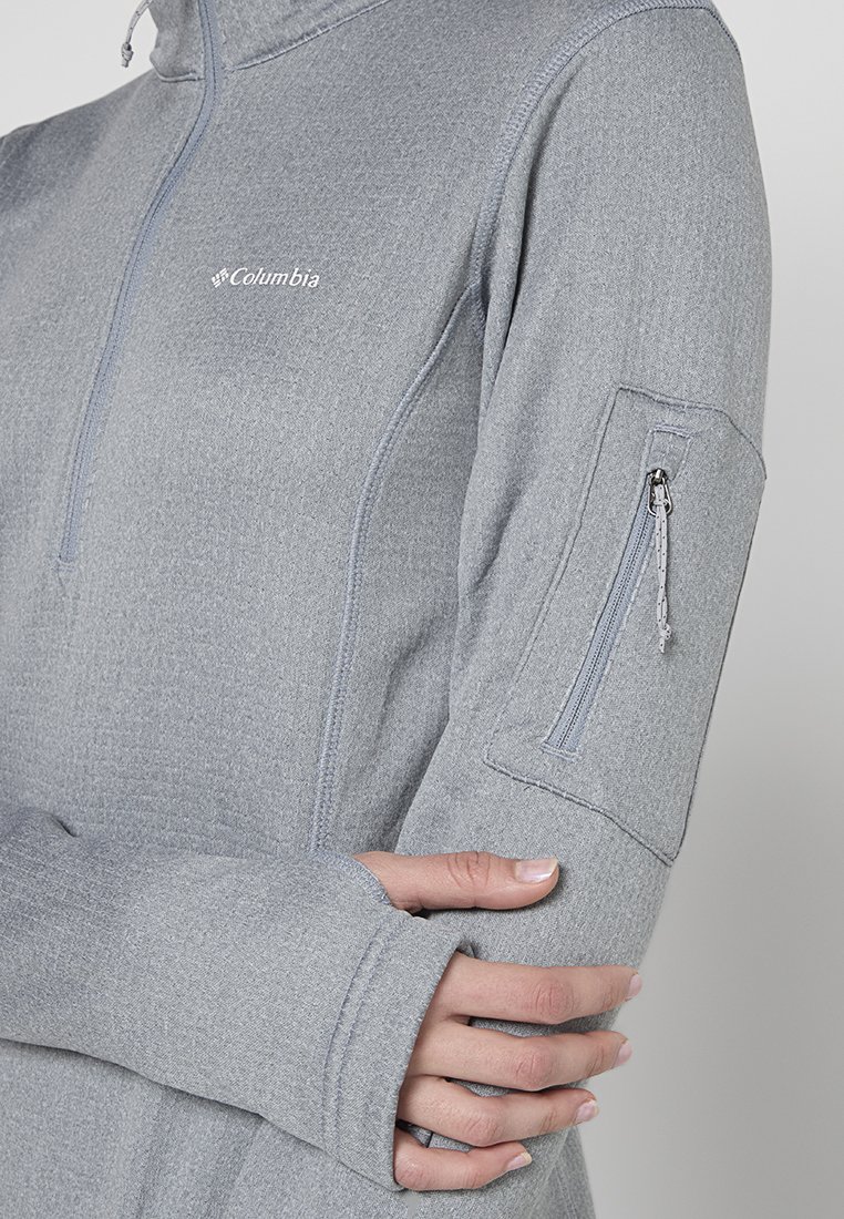 Pulóver gris de manga larga hecho de tejido texturizado. Presenta un cierre de media cremallera en la parte delantera y un bolsillo con cremallera en la manga izquierda; logo en el pecho.