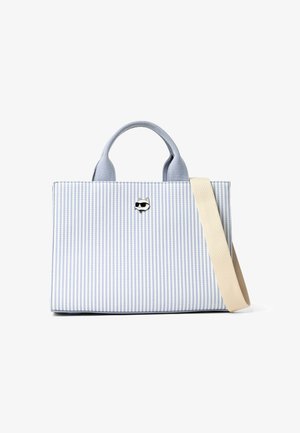 Τσάντα tote με κάθετες ρίγες σε μπλε και λευκό, κοντές χειρολαβές, μπεζ λουρί ώμου και μικρό καρφίτσα με τη μορφή γάτας που φορά γυαλιά ηλίου στο μπροστινό μέρος.