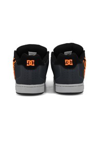 DC-Sneaker mit einem Obermaterial aus dunkelgrauem Leder, schwarzer Mesh-Fütterung, orangen Logo-Akzenten an den Seiten und einer grauen Gummisohle.