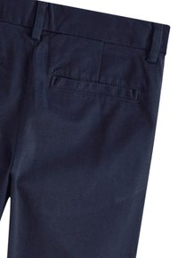 Tamsiai mėlynos formalaus stiliaus kelnės su diržo kilpelėmis ir viena paslėpta kišenė gale dešinėje pusėje.