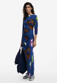 Langes blaues Kleid mit floralen Mustern in Orange, Pink und Weiß. Hergestellt aus weichem Stoff, mit langen Ärmeln und einem seitlichen Rüschendesign.