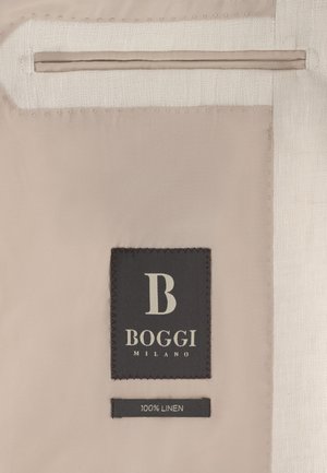 Tela beige con una etiqueta rectangular negra que dice "B BOGGI MILANO" y una etiqueta más pequeña debajo que indica "100% LINO."