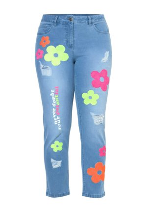 Blaue Jeans aus Denim mit mehrfarbigen großen Blumenpatschen, Used-Details und dem vertikal auf dem linken Bein aufgedruckten Text „Zweifle niemals an deinem Potenzial“.