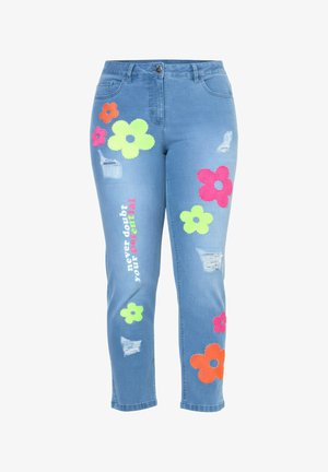 Blaue Jeans aus Denim mit mehrfarbigen großen Blumenpatschen, Used-Details und dem vertikal auf dem linken Bein aufgedruckten Text „Zweifle niemals an deinem Potenzial“.