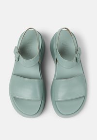 Light green leather sandals with a buckle, featuring a smooth texture, wide straps across the front, and a rounded, sculpted sole.