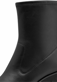 Bottine en cuir noir avec des détails de surpiqûres fines et un petit talon carré.
