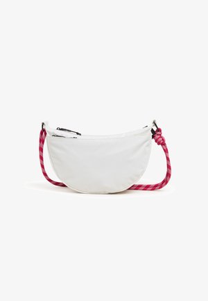 Biała torebka na ramię w kształcie półksiężyca z czarnymi zamkami błyskawicznymi i czerwoną w biały kratkę linką na jednym końcu.