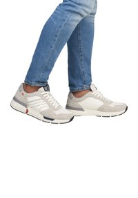 Baskets gris clair avec un mélange de suède et de mailles, présentant des accents blancs, des lacets et des semelles en caoutchouc noires, assorties à un jean.