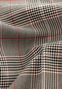 Tessuto intrecciato con motivo a quadri multicolore, con linee nere, crema e rosse. Texture liscia con un aspetto strutturato.