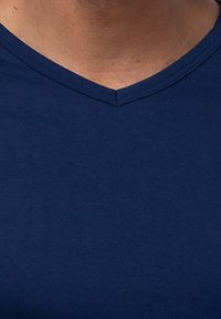 Granatowa bawełniana koszulka z dekoltem w serek. Tkanina jest gładka z lekką teksturą, bez widocznych wzorów ani akcentów.