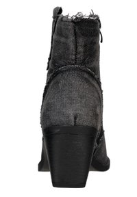 Botín de denim negro a los tobillos con un borde superior ligeramente deshilachado, cuerpo texturizado y un tacón negro moderado. Detalle de cremallera en el lateral.