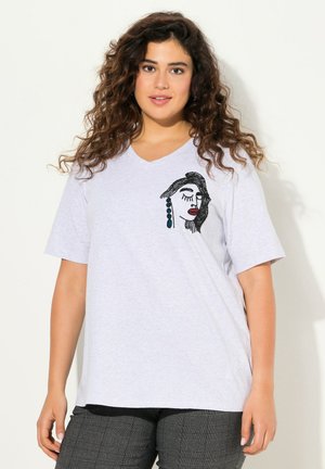 T-shirt en coton gris avec un col en V, ornée d'un motif de visage brodé noir et rouge à l'avant, assortie à un pantalon noir à motifs.