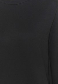 Suéter de algodón negro con un escote redondeado y una superficie suave y texturizada. Diseño sencillo sin patrones o acentos visibles.