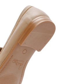 Scarpa in pelle beige con tomaia liscia, suola piatta in gomma tan e dettagli a rilievo sottili sulla suola. Nessun hardware o accenti visibili.