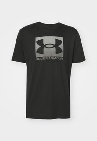 Svart bomull t-skjorte med korte ermer, med et stort grått Under Armour-logo på forsiden, glatt tekstur og rund hals.