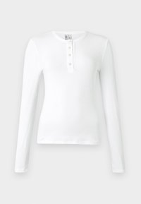 T-shirt blanc à manches longues en maille côtelée avec un col henley comprenant trois boutons. Texture lisse et design ajusté.