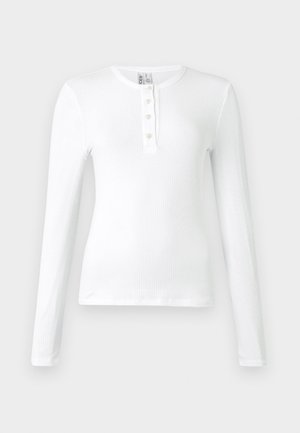 Witte lange mouwen ribbel top met een henley-hals en drie knopen. Soepele textuur en aansluitend ontwerp.