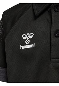 Svart pikétröja med en vit "hummel"-logotyp och textilstruktur. Har en knappkrage och mönstrade detaljer på ärmarna.