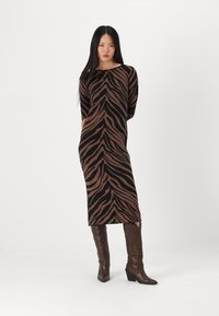Abito in maglia con motivo a strisce tigre marrone e nere, scollatura a girocollo, maniche lunghe, lunghezza midi, abbinato a stivali marroni al ginocchio.