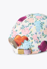Bloemenpet met meerkleurige bloemen en hartpatronen, met een gouden logo-accent en verstelbare band.