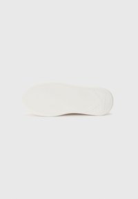 Semelle de sneaker blanche avec un motif de semelle ondulée, dotée d'une surface lisse, de bords arrondis et d'un design minimaliste.