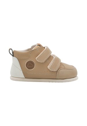 Zapatilla infantil beige y blanca con dos tiras de velcro y puntera texturizada sobre fondo blanco.