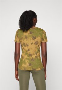 Kortärmad t-shirt i mjukt tyg, med ett batikmönster i gula, gröna och mörkbruna nyanser. Måttad design med böjd nederkant.