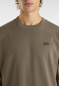 Olive green short-sleeve t-shirt made of soft cotton, featuring a small black Vans logo on the left chest area. Classic crew neck design.