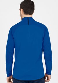 Maglietta sportiva a maniche lunghe di un blu brillante, realizzata in tessuto testurizzato, con colletto alto e dettagli neri sul retro.