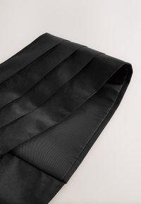 Black satin fabric with a smooth texture, featuring horizontal pleats and a folded edge, reflecting light subtly.