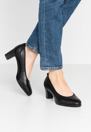 Czarne skórzane buty na wysokim obcasie z okrągłym czubkiem i fakturowanym wykończeniem. Posiadają obcas blokowy oraz prosty, minimalistyczny design.