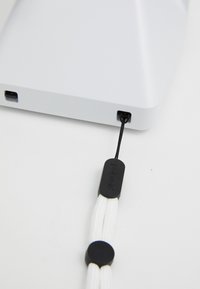 Dispositif de chargement rectangulaire blanc avec un port USB noir, doté d'un cordon noir et blanc relié par un matériel circulaire. Texture lisse.