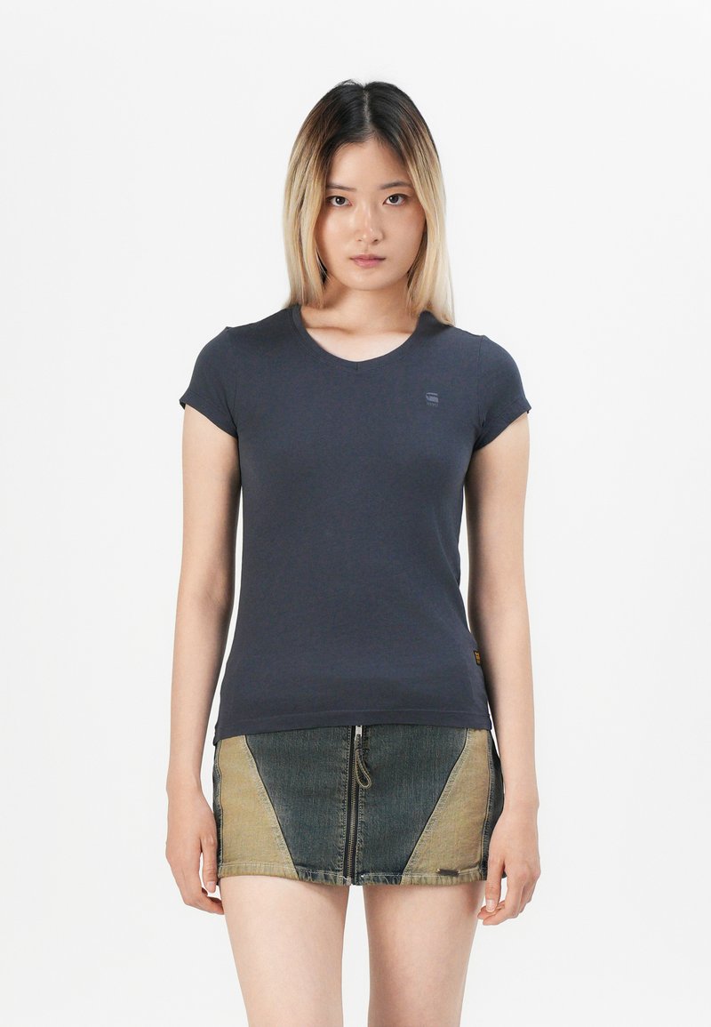 T-shirt aderente blu navy in morbido tessuto con maniche corte e scollatura rotonda. Abbinato a una gonna di jeans a fantasia con blocchi di colore.