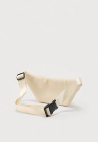 Μπεζ υφασμάτινη τσάντα μέσης με ρυθμιζόμενο ιμάντα και μαύρη πλαστική αγκράφα σε λευκό φόντο.