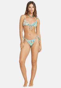 Costume da bagno floreale con sfondo azzurro chiaro, dotato di top a triangolo con chiusure a lacci e pantaloni con lacci laterali coordinati.