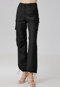 Pantalons cargo noirs avec une coupe droite, dotés de poches latérales, d'une fermeture à bouton et de poignets ajustables à cordon. Texture de tissu lisse.