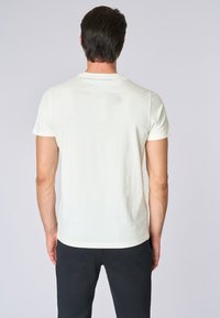 T-shirt fitted a maniche corte di colore crema chiaro. Realizzato in cotone morbido, presenta un collo rotondo e una texture liscia. Design semplice, senza motivi.