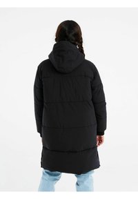 Cappotto imbottito nero con cappuccio, caratterizzato da cuciture verticali e spacchi laterali. Il design include polsini elasticizzati e un taglio lungo per un maggiore calore.