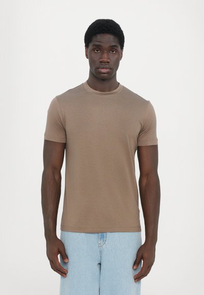 Brun t-shirt med korte ærmer og rund hals, lavet af glat stof. Bæres med lyseblå denim-jeans, der har en tætsiddende pasform og minimalistisk design.