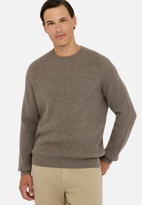 Brązowy sweter prążkowany z okrągłym dekoltem, długimi rękawami i luźnym krojem. Wykonany z teksturowanej tkaniny, z delikatnym wykończeniem hemu.