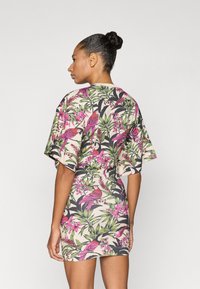 Φόρεμα με ανθικά μοτίβα που φέρουν ροζ πουλιά και πράσινα φύλλα, χαλαρή εφαρμογή, κοντά μανίκια και μπεζ βάση.