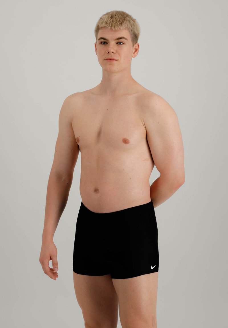 Sorte badeshorts med en jevn tekstur, med en logo foran. Midjebåndet er elastisk for en sikker passform.