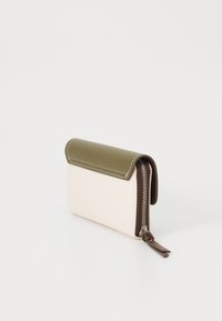 Väskan är i beige och olivgrön läder med en sydd kant, har en zip-stängning och en dragkedja av brunt läder.