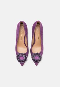 Scarpe con tacco alto in suede viola, con punte affusolate e decorazioni di perline sul davanti. Fodera interna liscia.