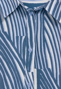 Camicia con righe verticali blu scuro e bianche, realizzata in tessuto morbido, con chiusura a bottoni e design con colletto a punta.