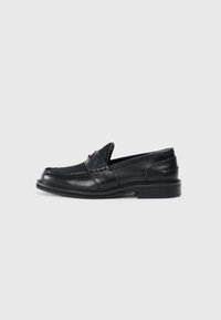 Sorte skinn loafers med rund tå, sydd detaljer, og slip-on design med en teksturert rem og en subtil rød aksent.